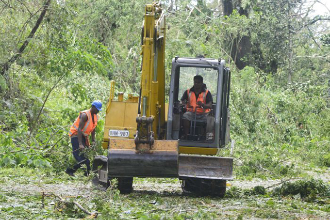 A bulldozer clearing trees off a road near Suva. Image: Joe Yaya