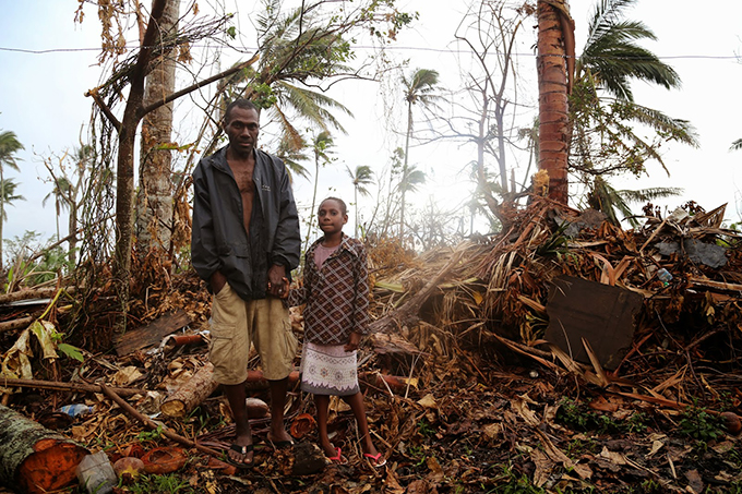 A ni-Vanuatu father and daughter stand in the wreckage of their home after Cyclone Pam. Image: UNICEF/Further Arts