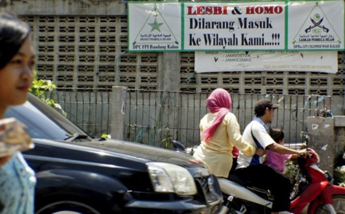 People negotiate the traffic past a banner put up by the hardline Islamic Defenders Front calling for gay people to leave the Cigondewah Kaler area in Bandung, West Java, Indonesia. Image: Antara Foto