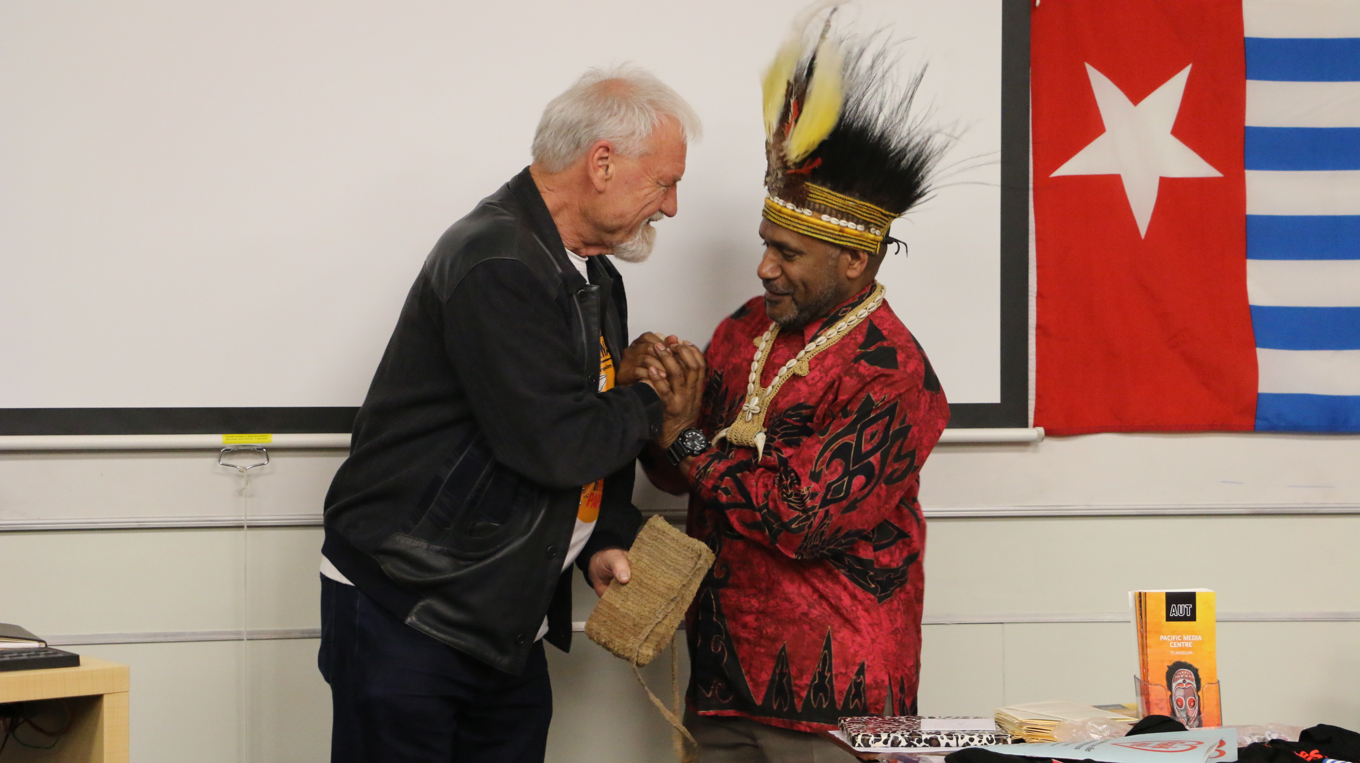 Free West Papua advocate Benny Wenda presents Pacific Media Centre Professor David Robie with a traditional “bilum” for his journalism about West Papuan freedom. Image: Kendall Hutt/PMC