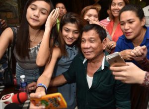 Philippines' President-elect Rodrigo Duterte poses for selfie pictures with supporters at his first media conference after winning the presidential election. Image: Philippine Daily Inquirer