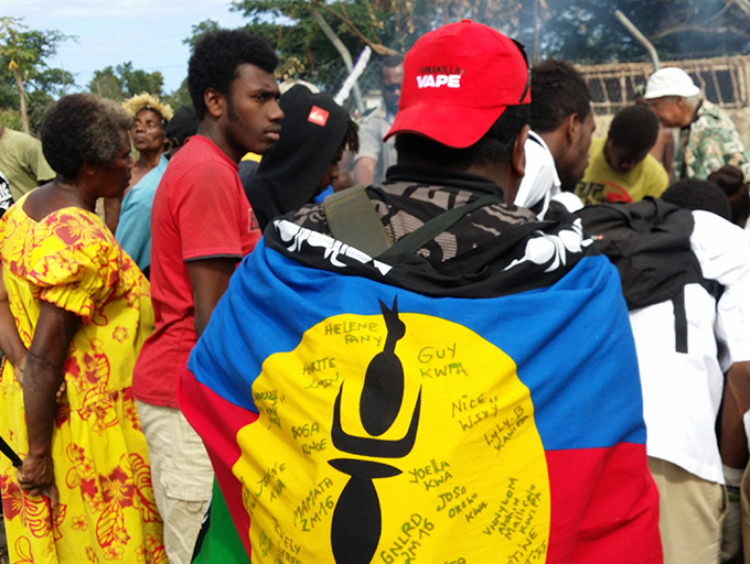 A Kanak wearing the Kanak flag watching a fire making demonstration at Tupunis. Image: David Robie/PMC