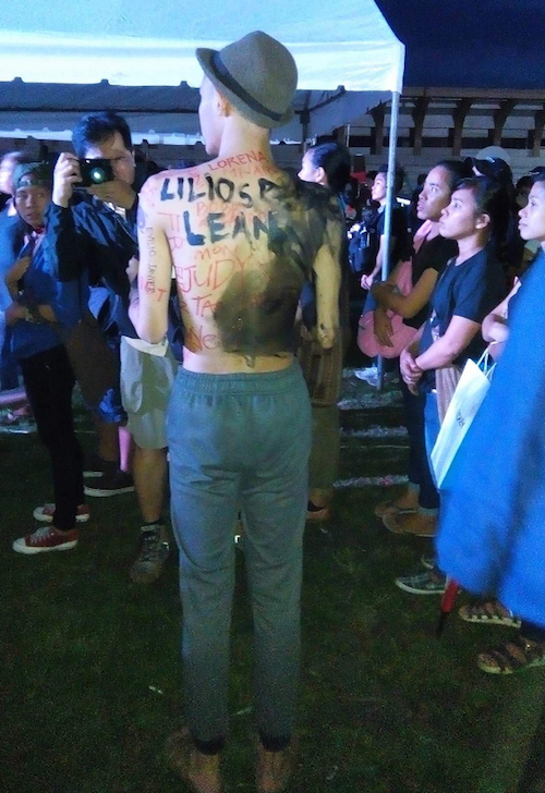 The shirtless young Filipino has names written on his back - victims of the Marcos dictatorship. Image: Becky Horton