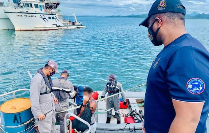 A Fiji Navy crewman hands over the survivors