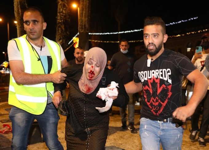 People helping an injured Palestinian woman