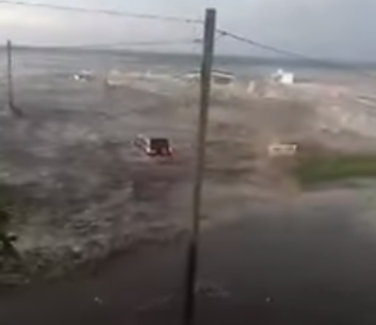 A vehicle being swept away by the tsunami wave on 'Eua