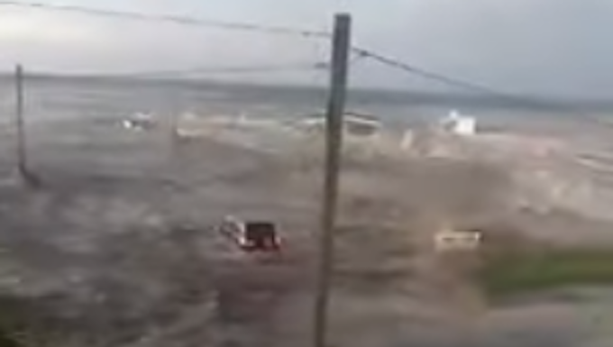 A vehicle being swept away by the tsunami wave on 'Eua