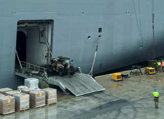 Workers load the HMAS Adelaide with supplies for Tonga