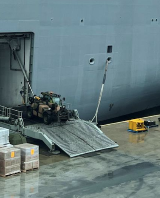Workers load the HMAS Adelaide with supplies for Tonga