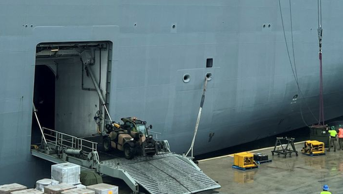 Workers load the HMAS Adelaide with supplies for Tonga