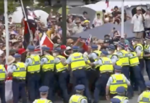 Anti-vaxxer protesters try to break through a police barrier on New Zealand's Parliament grounds
