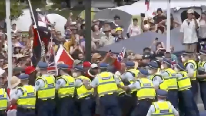 Anti-vaxxer protesters try to break through a police barrier on New Zealand's Parliament grounds