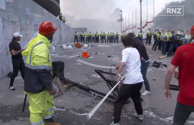 Protesters whack another protestor with a tent pole