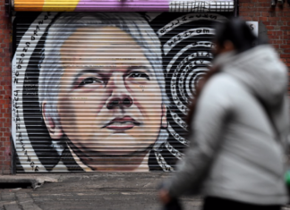 People walk past a mural of Julian Assange