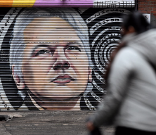 People walk past a mural of Julian Assange