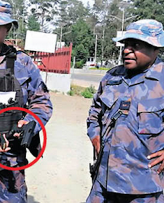 PNG police officers with a gun allegedly seized from an election candidate