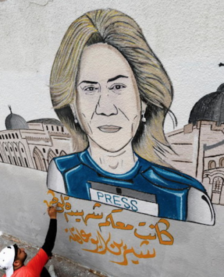 A street artist adds to a mural of Al Jazeera reporter Shireen Abu Akleh
