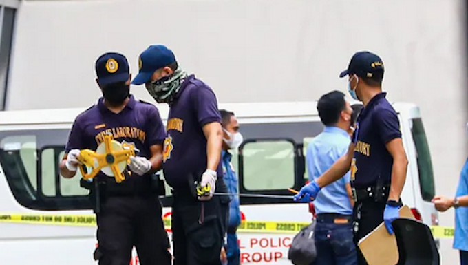 Philippine police inspect the assassination crime scene at the Ateneo de Manila University