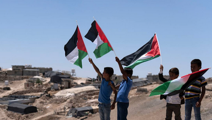 Palestinian children wave the national flags at the West Bank village of Masafer Yatta