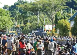 Papuan protesters sit on the ground in Meepago
