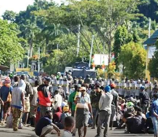 Papuan protesters sit on the ground in Meepago