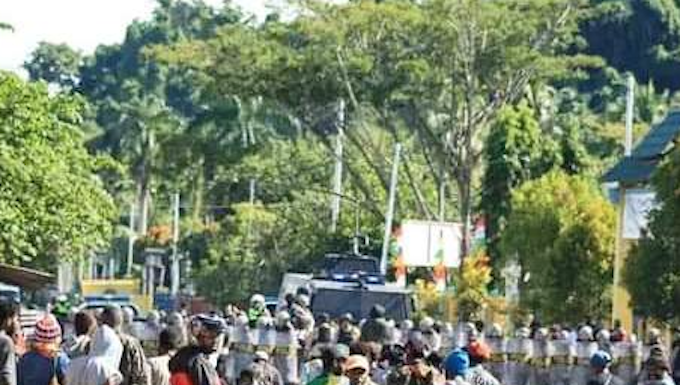 Papuan protesters sit on the ground in Meepago