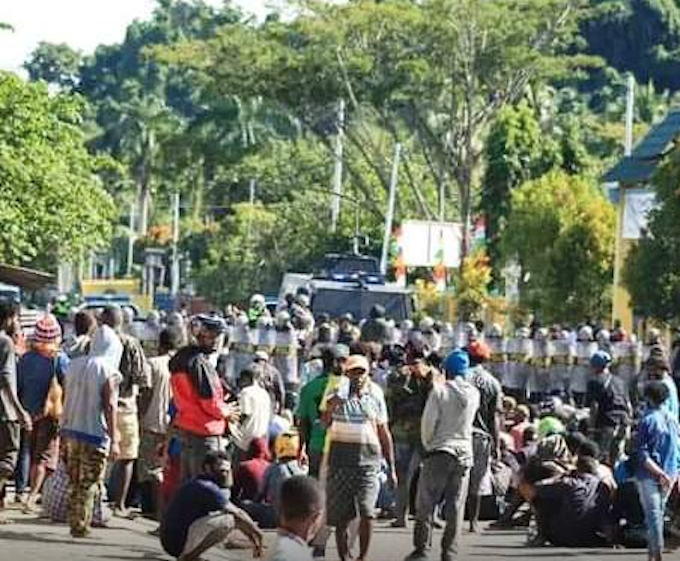 Papuan protesters sit on the ground in Meepago