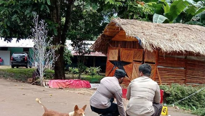 Police gather evidence near the site of a bomb explosion that took place outside the house of Jubi editor Victor Mambor