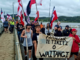 People holding a "Honour Te Tiriti o Waitangi" sign at Waitangi.