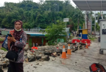 A woman in Jayapura stands next to a collapsed wall after the quake