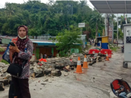 A woman in Jayapura stands next to a collapsed wall after the quake