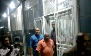 Suspended Police Commissioner Sitiveni Qiliho (right in shadows walking outside Suva's CID headquarters)