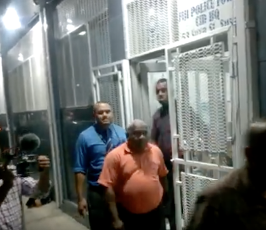 Suspended Police Commissioner Sitiveni Qiliho (right in shadows walking outside Suva's CID headquarters)