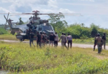 Indonesian military and police personnel surround a helicopter in Kenyam district, Nduga regency, Papua Highlands, in February