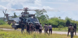 Indonesian military and police personnel surround a helicopter in Kenyam district, Nduga regency, Papua Highlands, in February