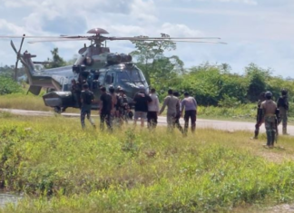 Indonesian military and police personnel surround a helicopter in Kenyam district, Nduga regency, Papua Highlands, in February