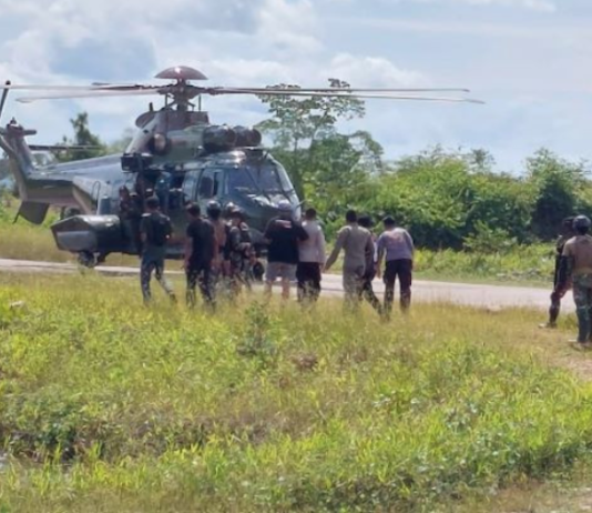 Indonesian military and police personnel surround a helicopter in Kenyam district, Nduga regency, Papua Highlands, in February