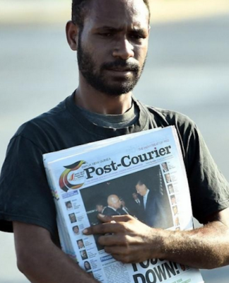 A PNG Post-Courier newsboy on the streets in Port Moresby