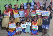 A group of Papuan women and children wave Melanesian state flags