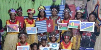 A group of Papuan women and children wave Melanesian state flags