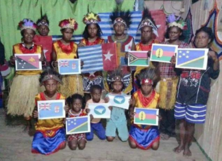 A group of Papuan women and children wave Melanesian state flags