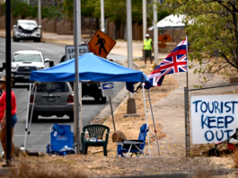 The flag of Hawai'i waves beside a sign reading "Tourist(s) Keep Out" in the aftermath of the Maui wildfires