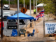 The flag of Hawai'i waves beside a sign reading "Tourist(s) Keep Out" in the aftermath of the Maui wildfires
