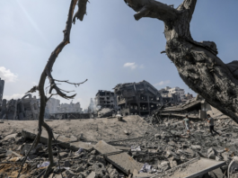 Palestinians walk amid the rubble of a destroyed area in the Al-Ramal neighborhood in Gaza
