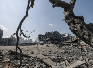 Palestinians walk amid the rubble of a destroyed area in the Al-Ramal neighborhood in Gaza