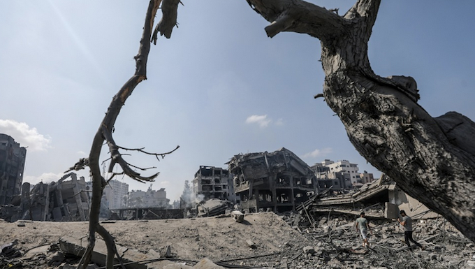 Palestinians walk amid the rubble of a destroyed area in the Al-Ramal neighborhood in Gaza