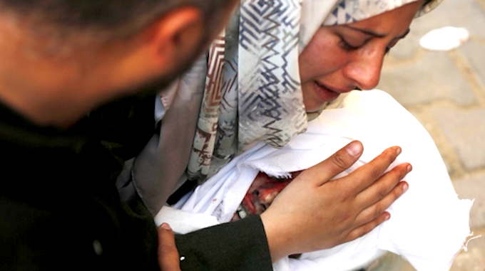 A Palestinian mother and family hug the dead body of their child who died in an Israeli attack in Deir al-Balah, Gaza