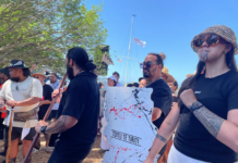 Protesters are carrying wooden signs shaped as the te tiriti o Waitangi