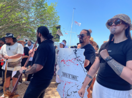Protesters are carrying wooden signs shaped as the te tiriti o Waitangi