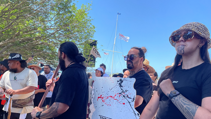 Protesters are carrying wooden signs shaped as the te tiriti o Waitangi